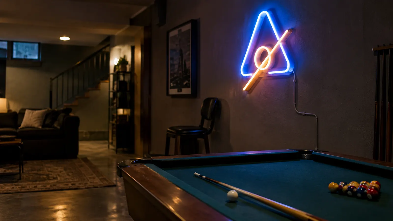 A glowing neon sign mounted on a wall above a pool table in a dim basement, the cord held flat with adhesive clips