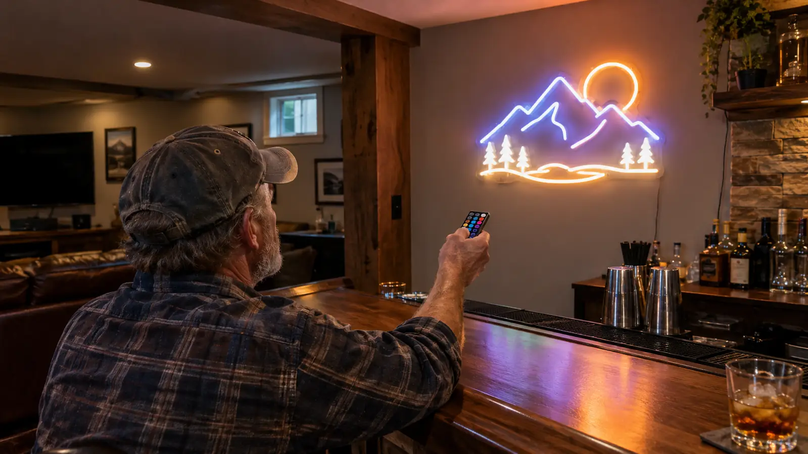 A hand using a small remote to turn on a custom neon sign mounted on a wall above a bar counter.
